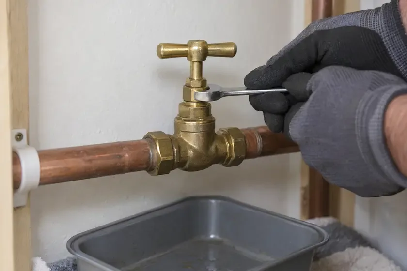 Plumber repairing the gland nut of a brass main water stopcock.